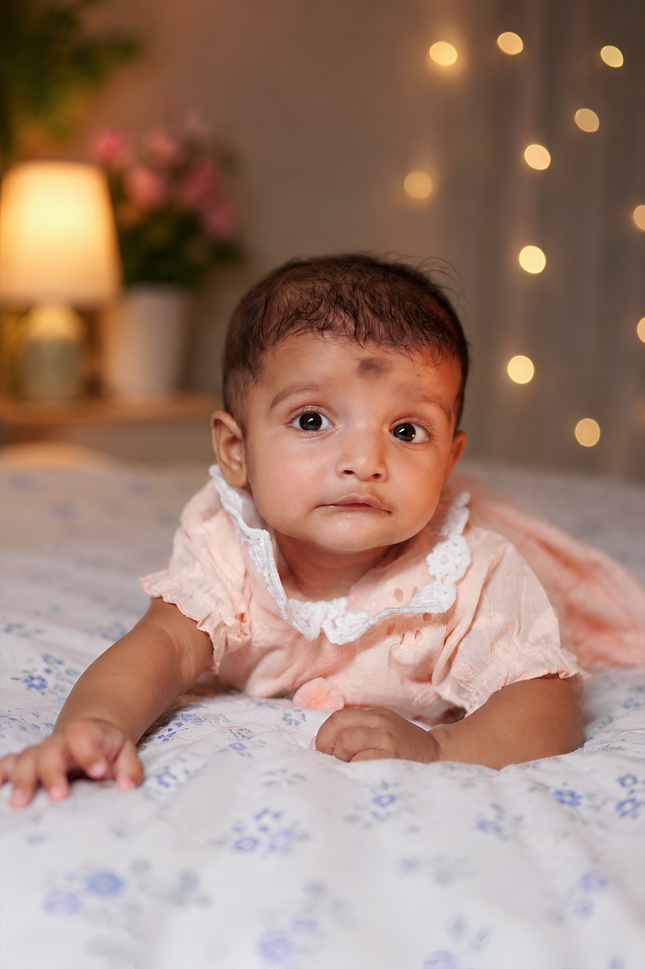 Baby crawling on soft floral bedspread with chandan phota