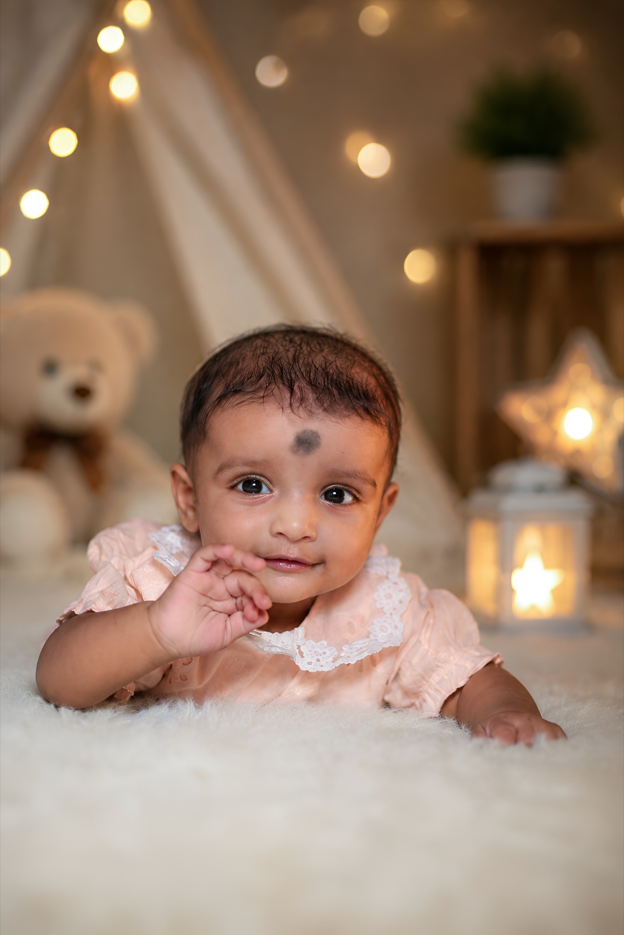 Baby sitting in cozy teepee tent with glowing star lantern
