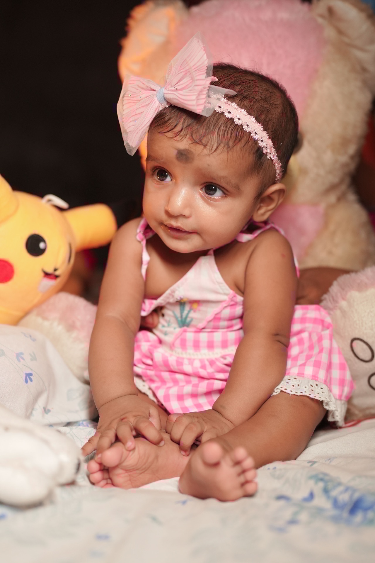 Baby in pink checkered dress with Pikachu plushie