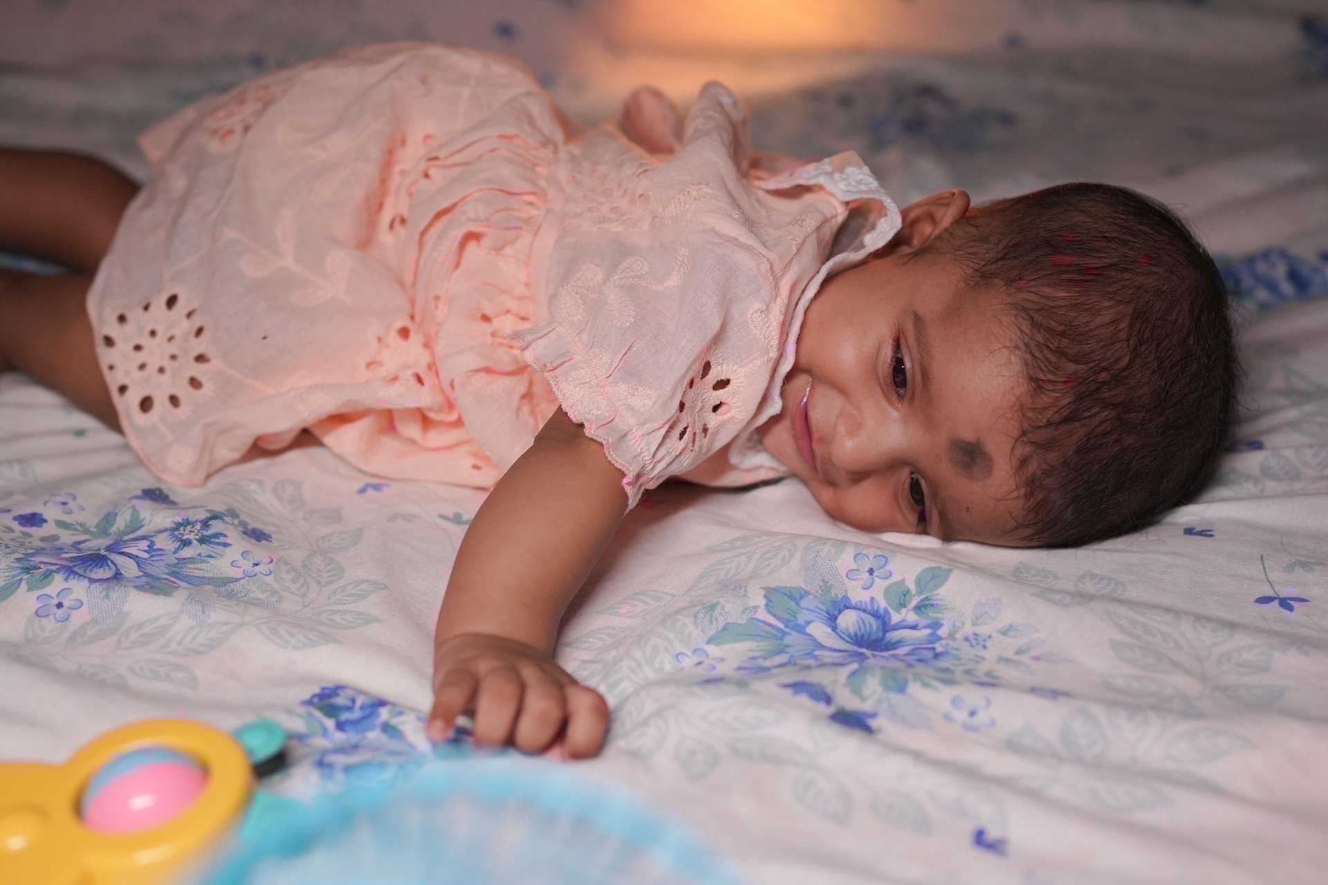 Playful baby giggling and reaching for colorful rattle