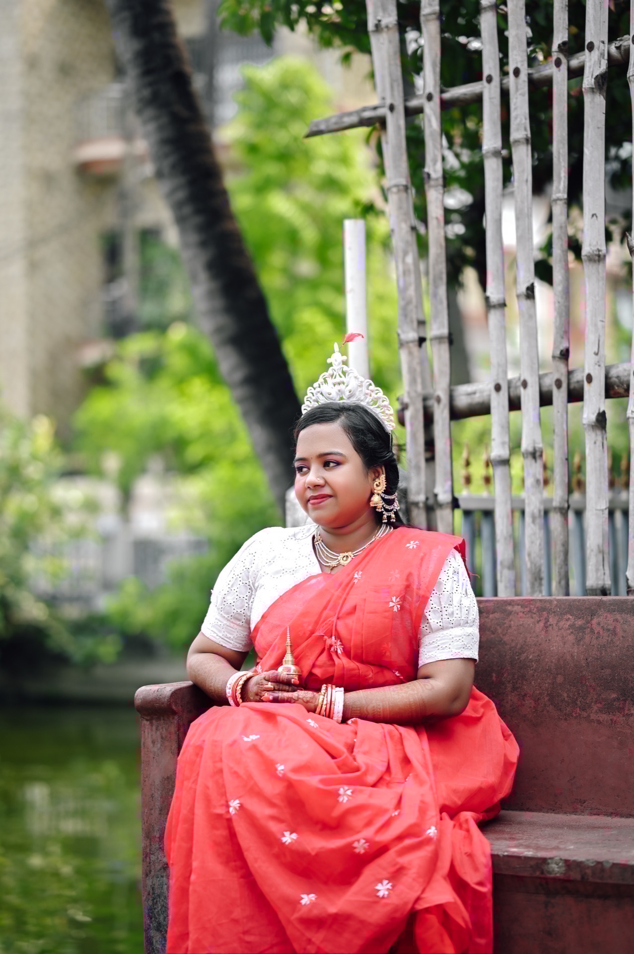 Bride with Mukut & gachkouto seated by peaceful lakeside